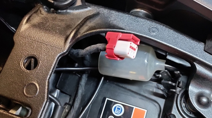 Motard soulevant la selle pour localiser la prise diagnostic moto près de la batterie