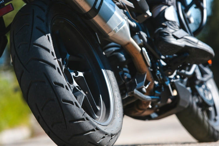 Gros plan sur le pneu arriere et l echappement d une moto en route