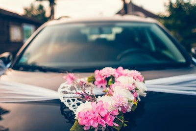 Capot de voiture de mariage noire decore de fleurs roses et blanches et d un voile blanc