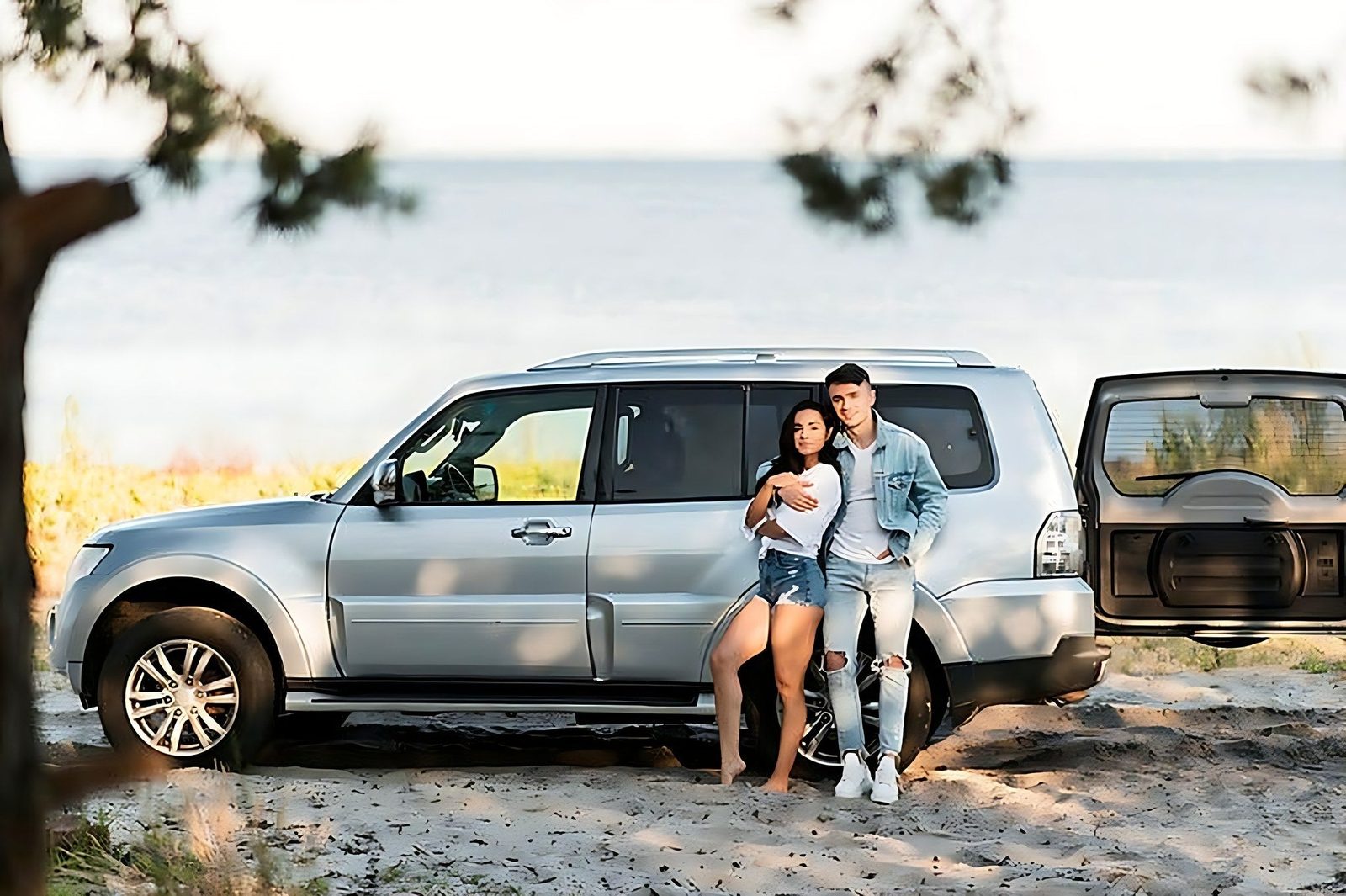 Couple posant devant un vehicule surleve de type SUV lors un voyage au bord de eau