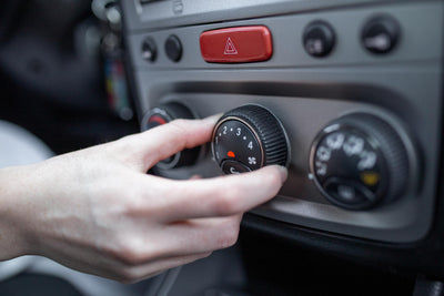 Main réglant le bouton rotatif de la climatisation et du chauffage d'une voiture