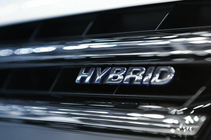 Gros plan sur le logo chromé Hybrid fixé sur la calandre noire d'une voiture
