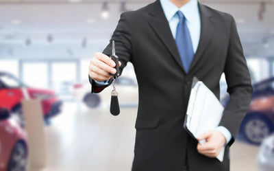 Conseiller en concession automobile tenant une clé de voiture pour un leasing
