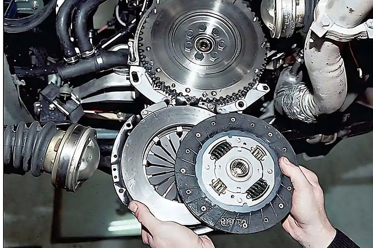Mains d un mecanicien tenant un disque et un plateau d embrayage face au volant moteur