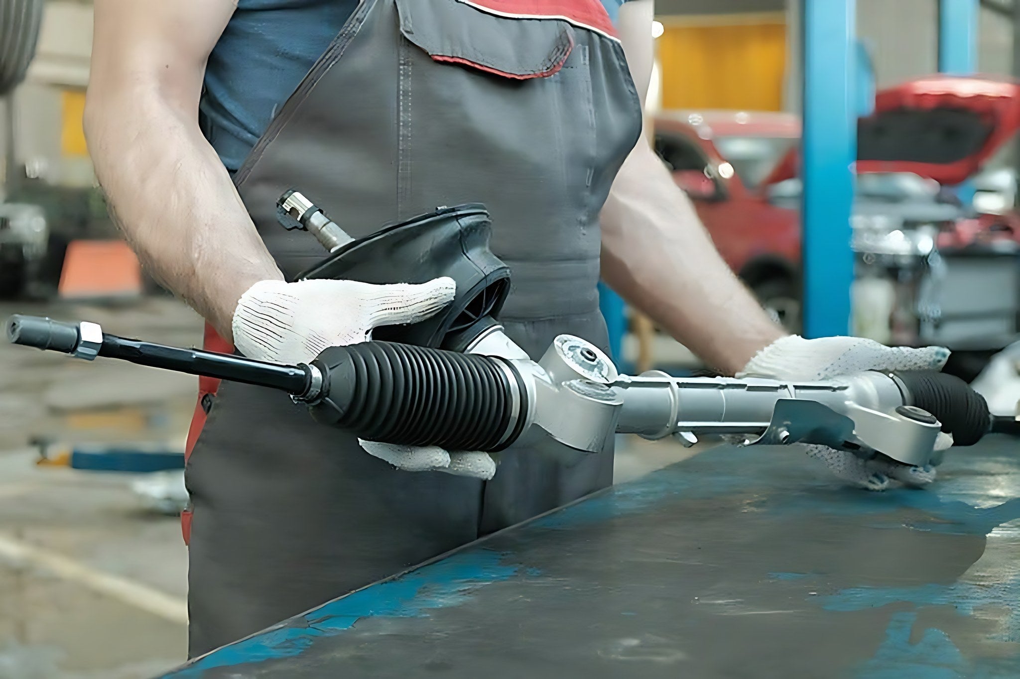 Mecanicien presentant une cremaillere de direction neuve dans un garage automobile