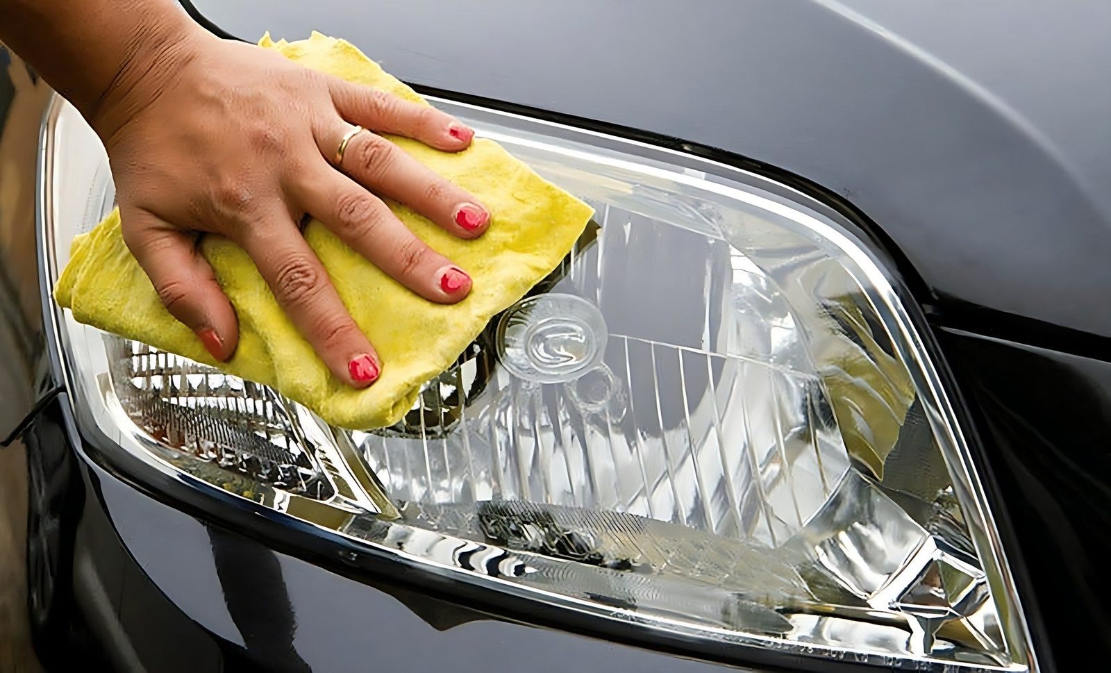 Nettoyage manuel du phare avant d une voiture noire avec un chiffon jaune
