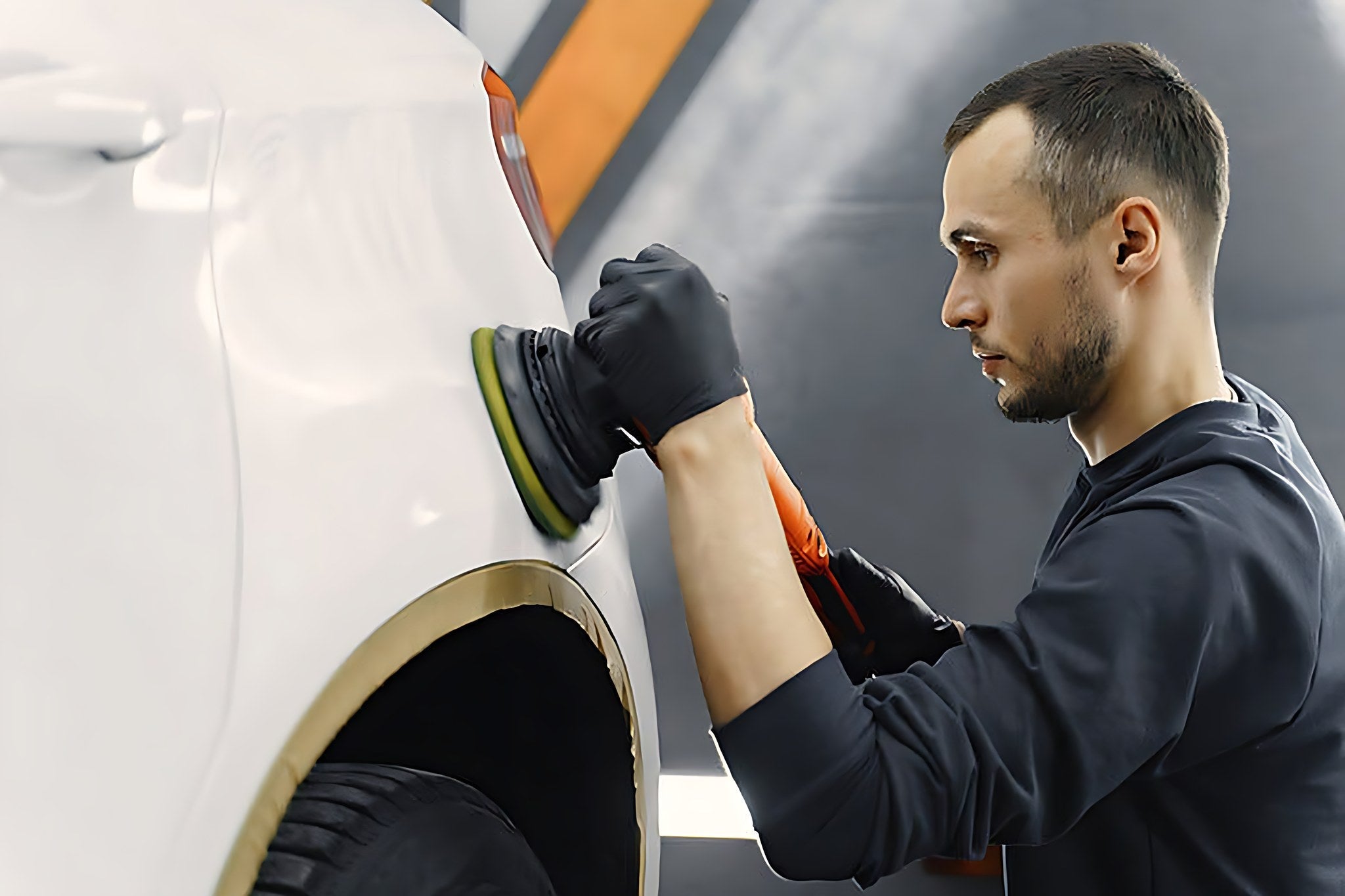 Professionnel utilisant une polisseuse pour effacer une rayure sur une carrosserie blanche