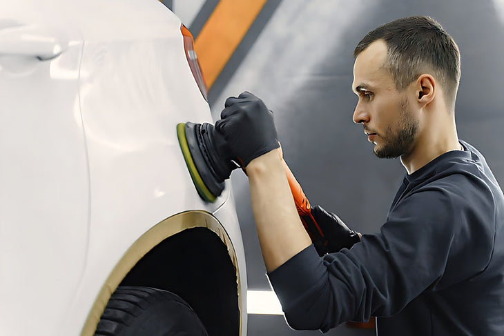 Professionnel utilisant une polisseuse pour effacer une rayure sur une carrosserie blanche