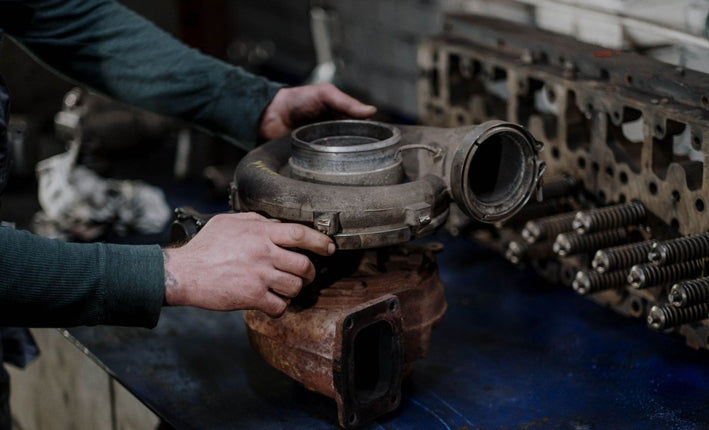 Mécanicien inspectant un turbo cassé en roulant pour diagnostic et réparation de voiture
