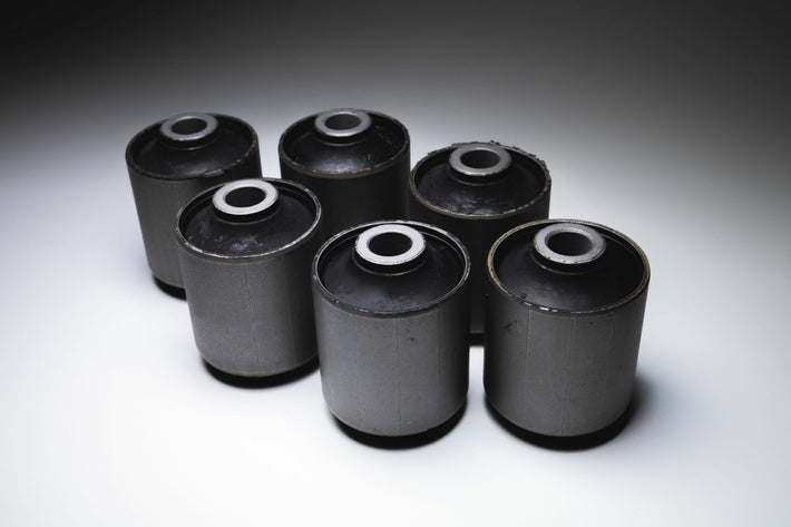 Lot de six silent blocs de suspension automobile neufs posés sur un fond blanc