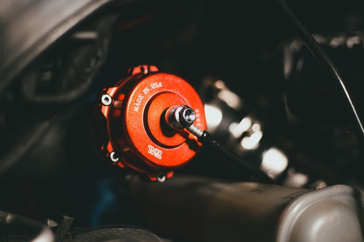 Détail d un capteur de pression et d une wastegate de turbo rouge installés sur un moteur