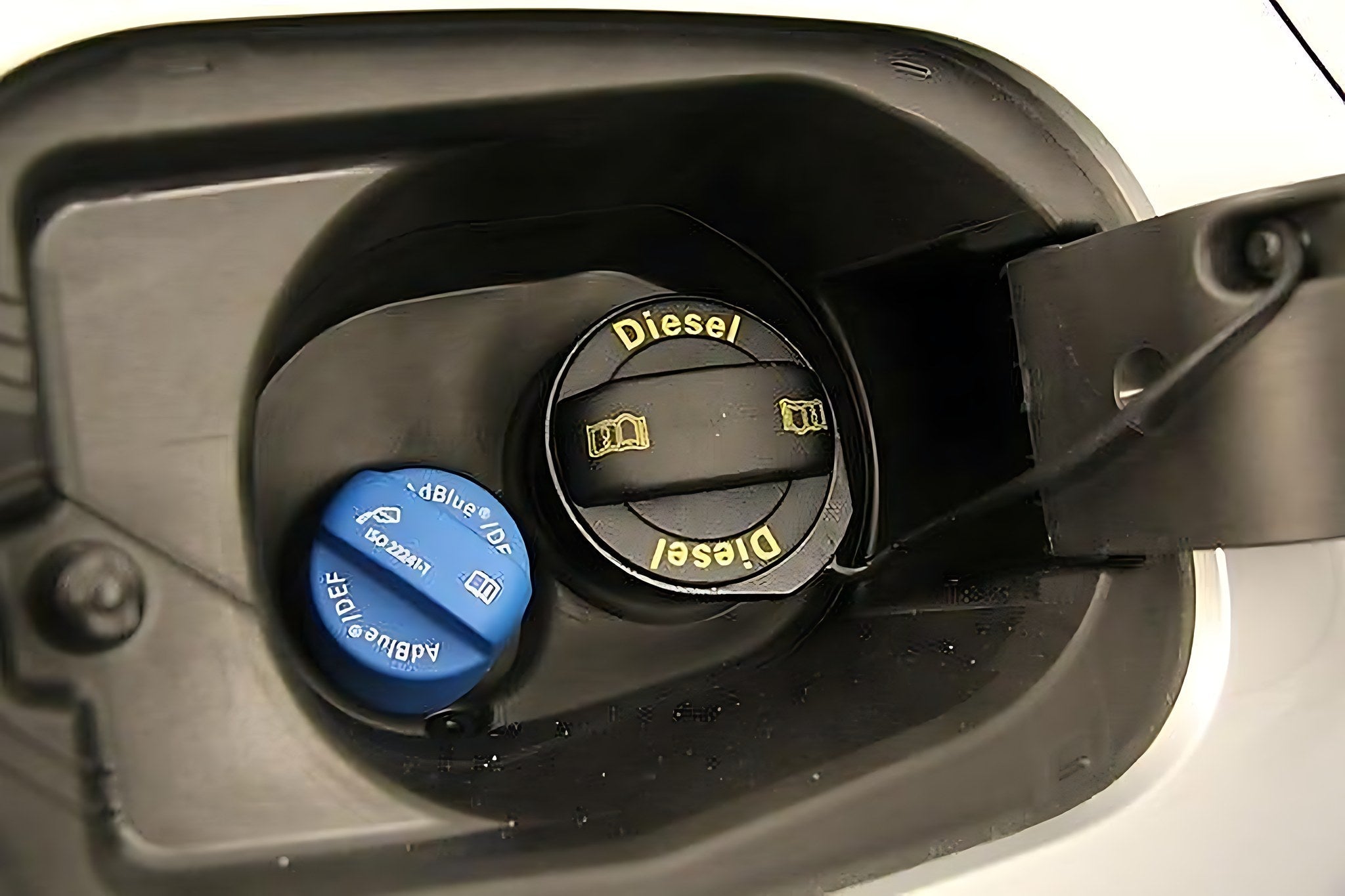 Trappe de carburant ouverte avec bouchon noir de gasoil et bouchon bleu de reservoir AdBlue