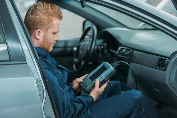 Technicien assis dans une voiture utilisant une valise de diagnostic Launch branchée à l OBD