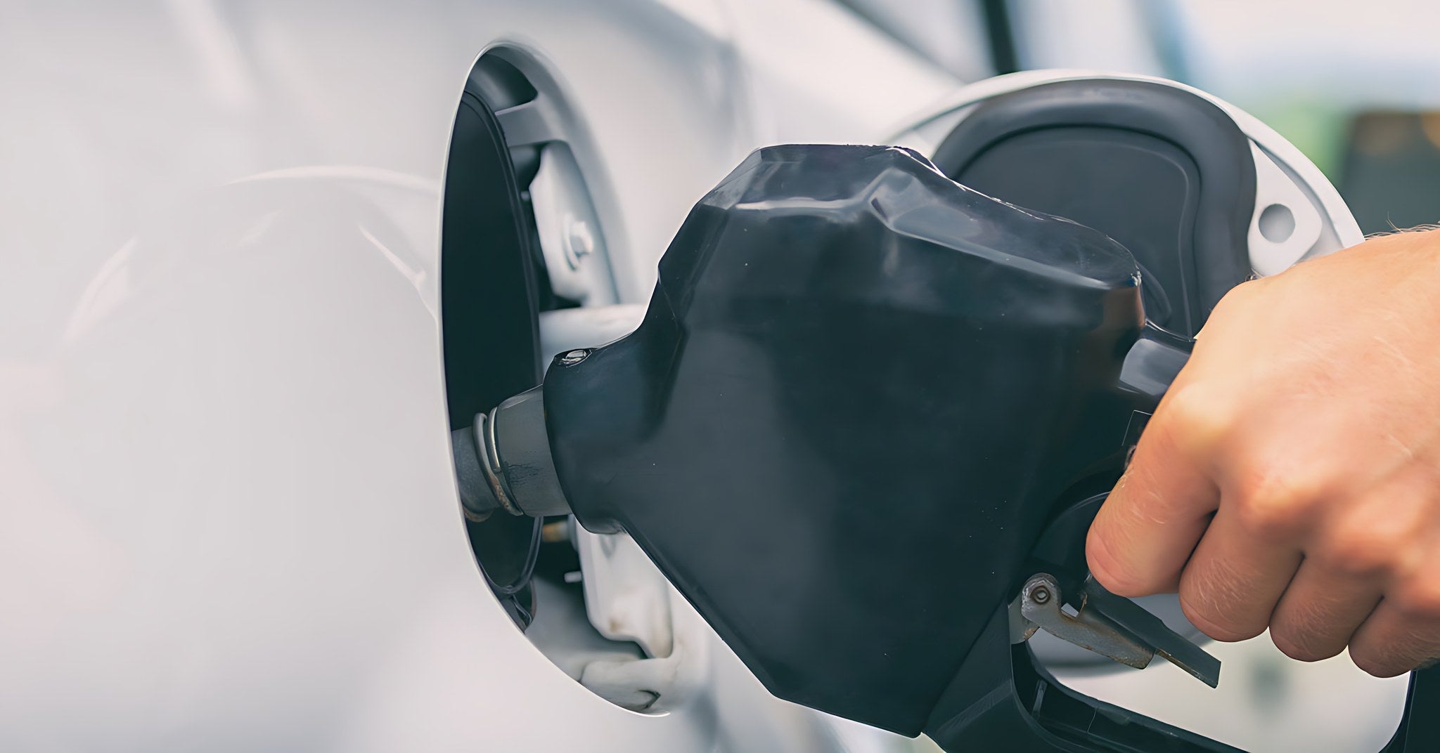 Main inserant un pistolet de carburant dans le reservoir d une voiture blanche pour faire le plein de bioethanol E85