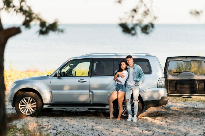 Couple posant devant un 4x4 argenté lors d un voyage au bord de l eau
