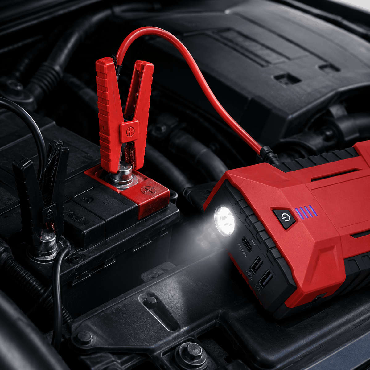 Booster de batterie de voiture avec pinces de démarrage rouge et noire connectées sous le capot