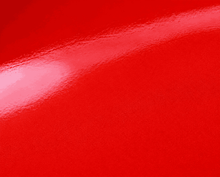 Gros plan sur une surface de carrosserie rouge brillant avec reflet lumineux