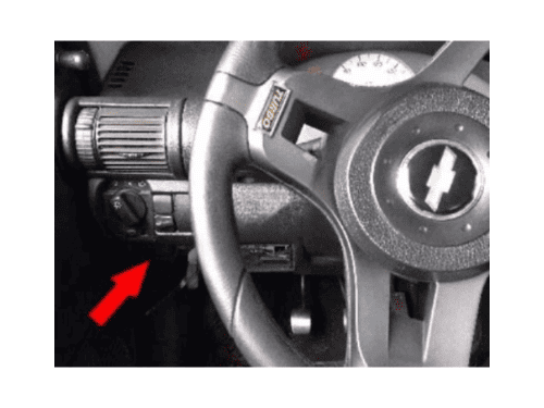 Flèche rouge indiquant l'emplacement de la boîte à fusibles sous le tableau de bord d'une Chevrolet Corsa Wind