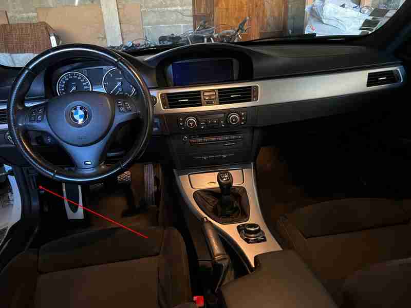 Fleche rouge pointant vers l emplacement de la prise OBD sous le volant d une BMW Serie 3 E91