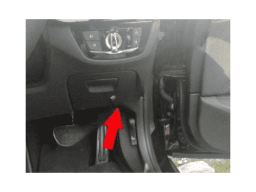 Une flèche rouge indique l'emplacement de la prise OBD sous le tableau de bord d'une BMW Série 5 G30 G31