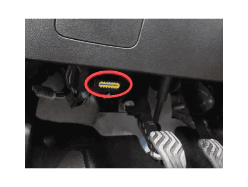 Une flèche rouge indique l'emplacement de la prise OBD2 sur le tableau de bord d'une Dacia Logan