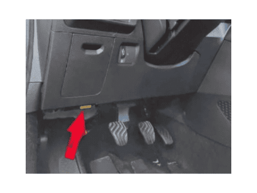 Une flèche rouge indique l'emplacement de la prise OBD2 sous le volant d'une Dacia Logan 3