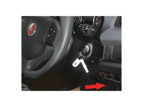 Une flèche rouge indique l'emplacement de la prise OBD de diagnostic sur un tableau de bord de Fiat Doblo 2