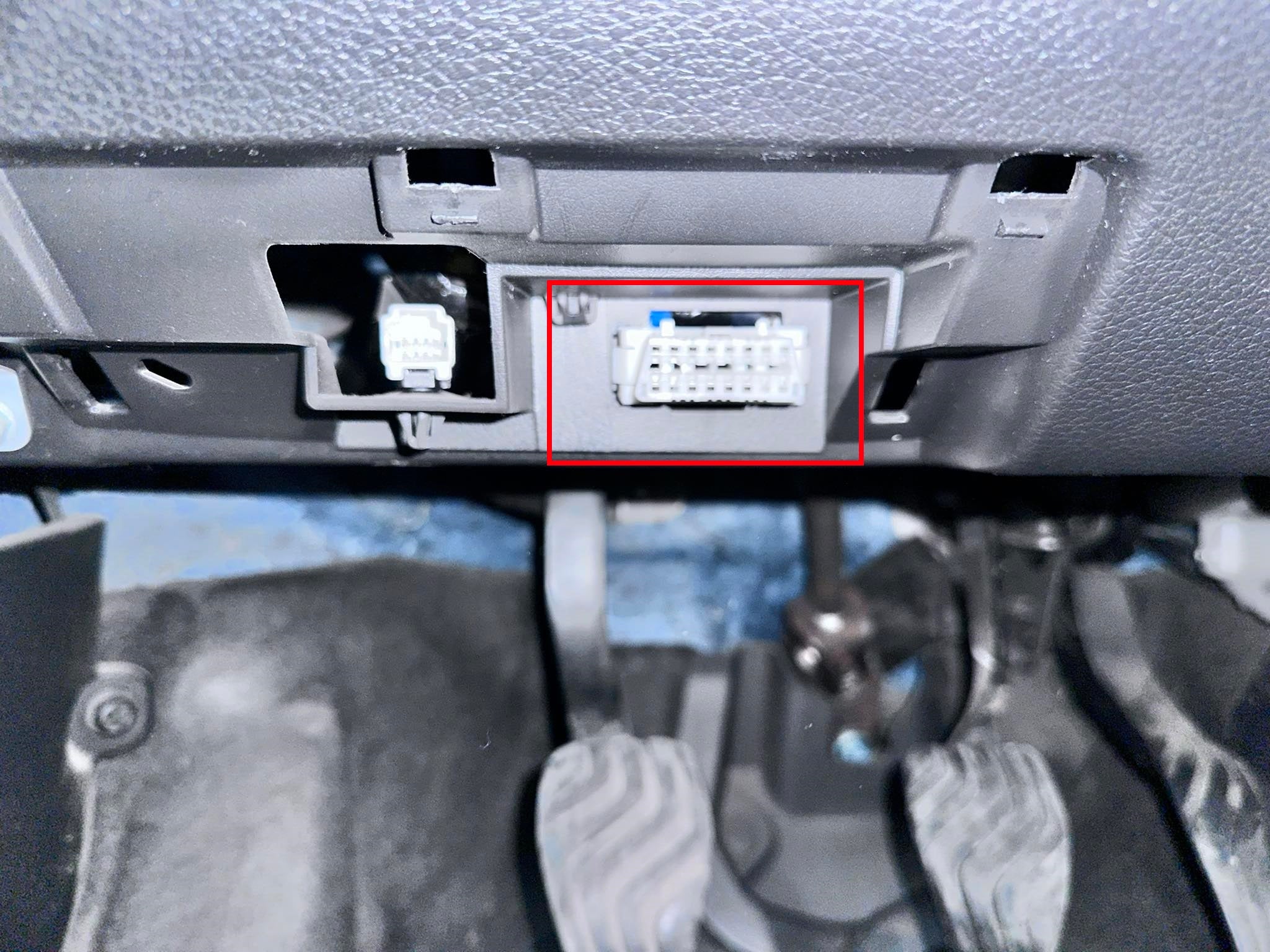 Vue de la prise OBD de diagnostic située sous le tableau de bord au dessus du pédalier