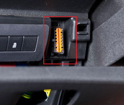 Gros plan sur l emplacement d une prise OBD de couleur orange sous le tableau de bord