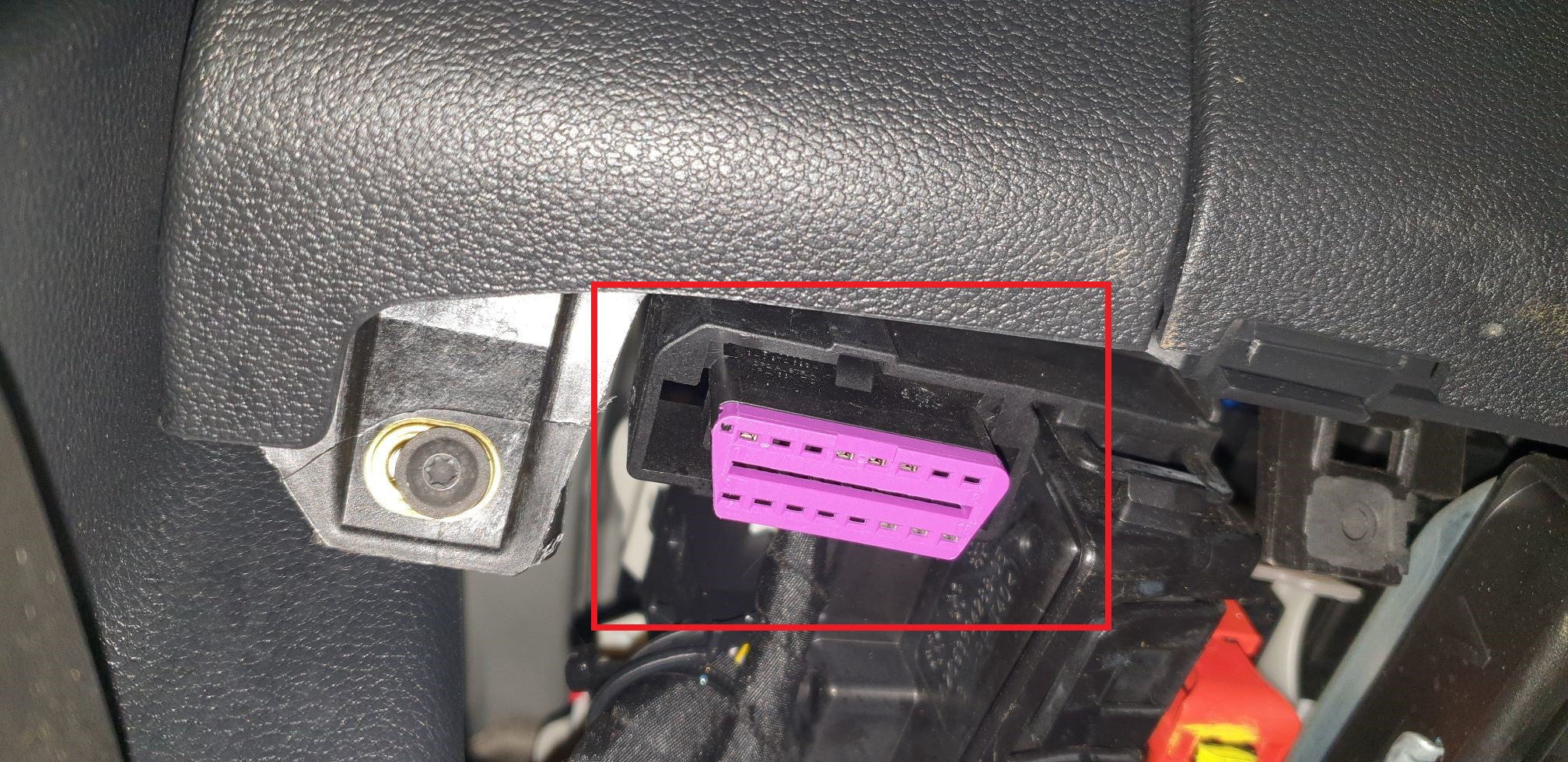 Prise de diagnostic OBD de couleur violette sous le tableau de bord d'un véhicule