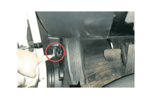 Doigt pointant vers l'emplacement de la prise de diagnostic OBD2 sur une BMW X1
