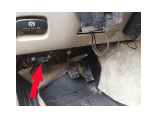 Une flèche rouge indique l'emplacement de la prise OBD2 sous le tableau de bord d'une Chevrolet Astro