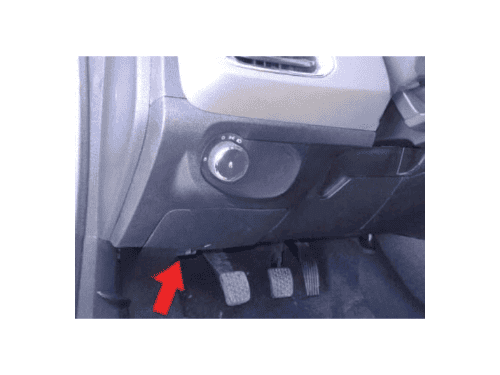 Une flèche rouge indique l'emplacement de la prise OBD2 sous le pédalier d'une Chevrolet Prisma 2