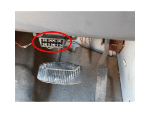 Prise de diagnostic OBD2 entouree en rouge sous le tableau de bord d une Ford Econoline