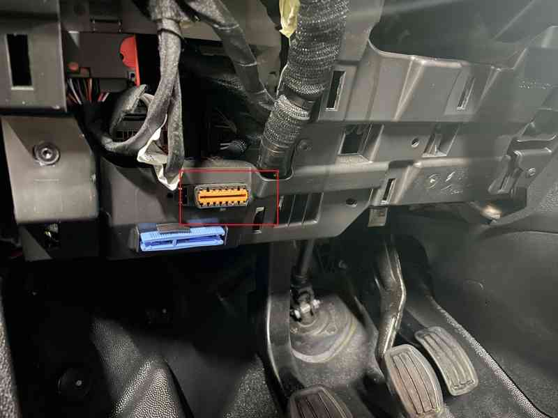 Emplacement de la prise de diagnostic OBD2 orange sous le tableau de bord d'un Peugeot Partner 3