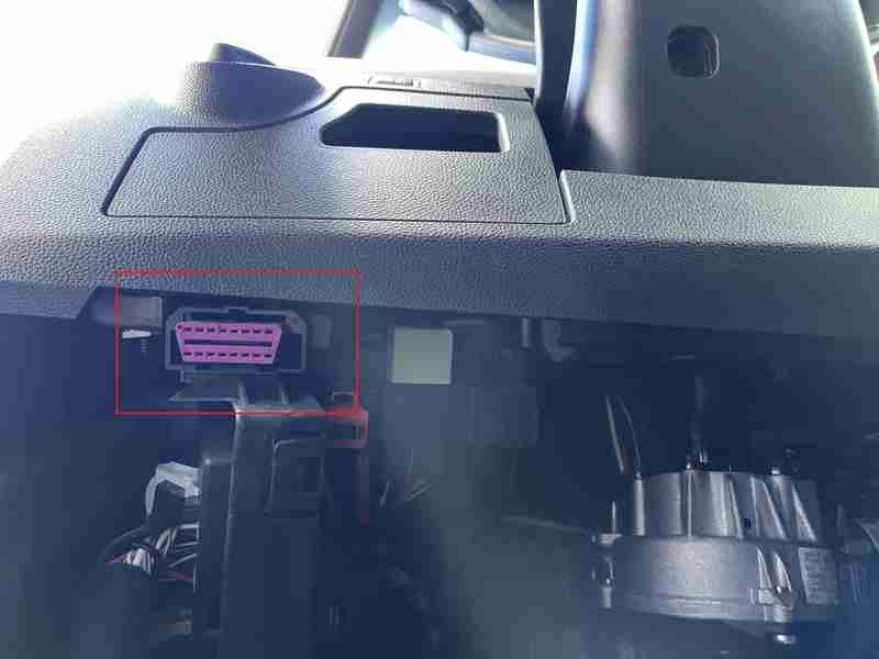 Photo montrant l emplacement de la prise OBD2 de couleur rose sous le tableau de bord d une Seat Arona