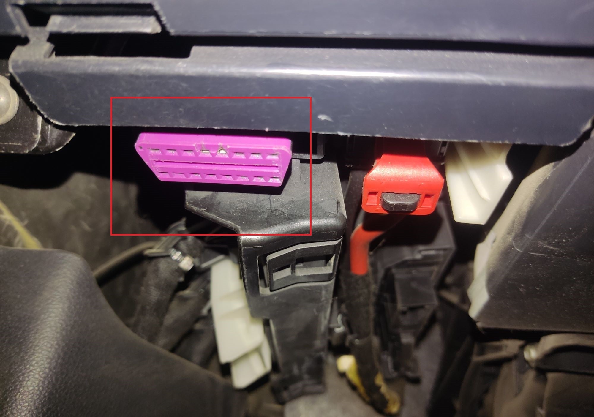 Localisation de la prise de diagnostic OBD2 violette sous le tableau de bord