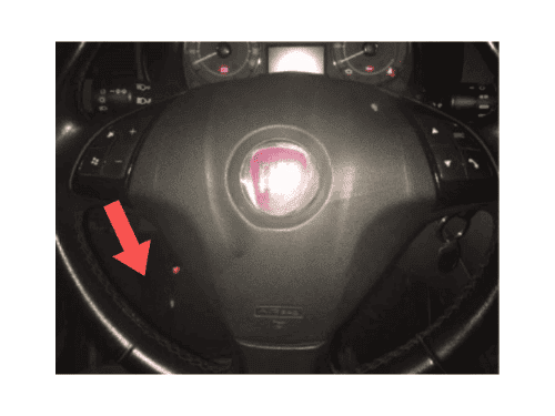 Flèche rouge montrant l emplacement de la prise OBD derrière le volant d une Fiat Linea