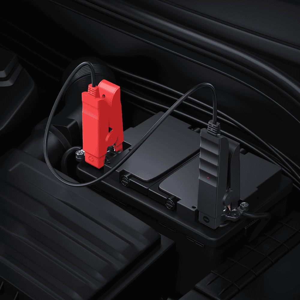 Pinces de démarrage rouge et noire branchées sur les cosses d'une batterie de voiture