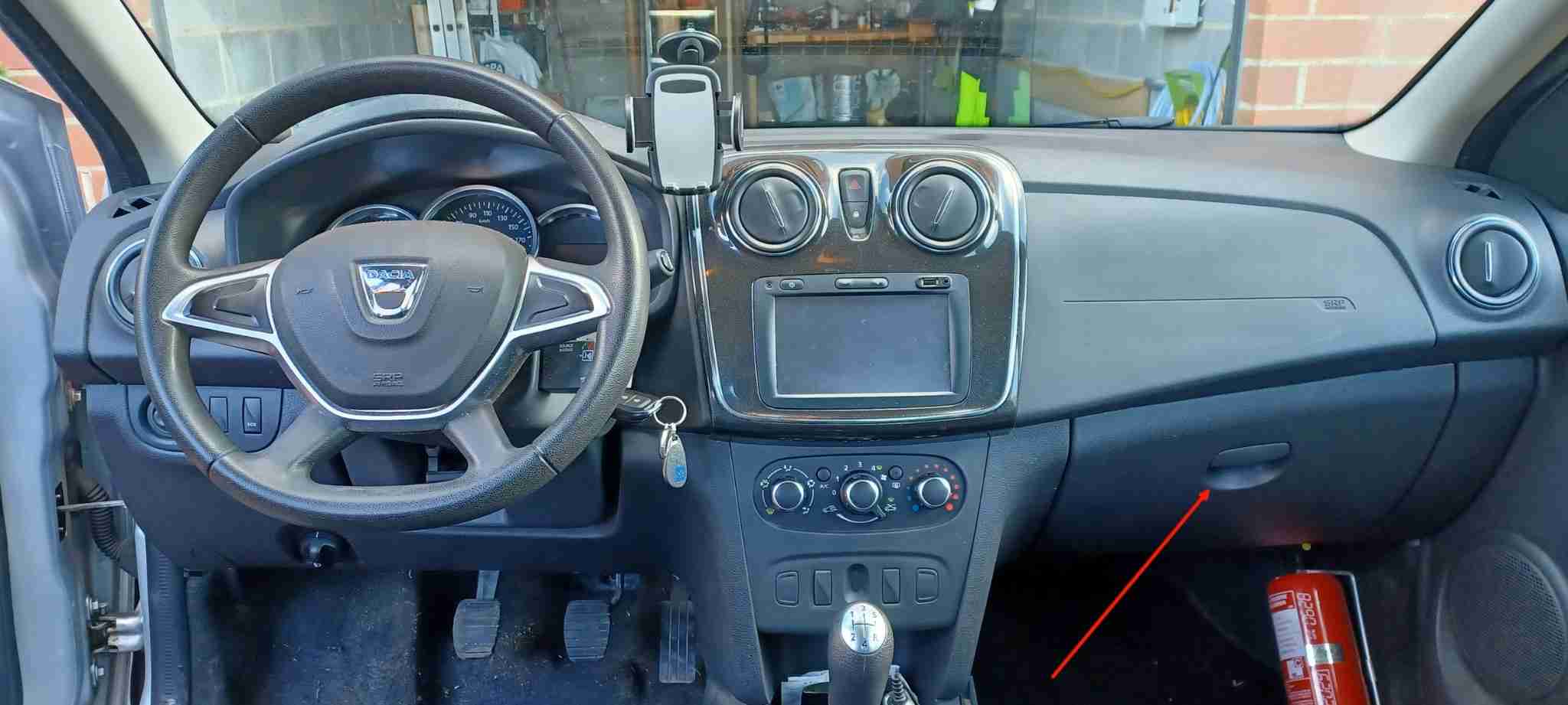 Vue intérieure de l'habitacle d'une Dacia Logan 2 avec flèche indiquant la boîte à gants