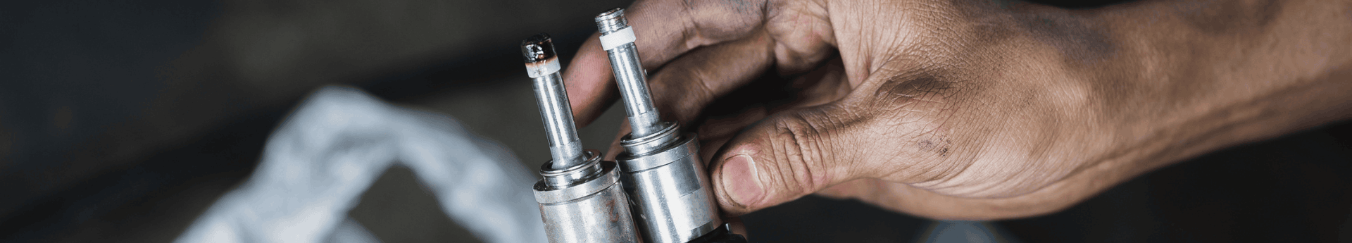 Comparaison de deux injecteurs de voiture tenus par les mains sales d'un mécanicien
