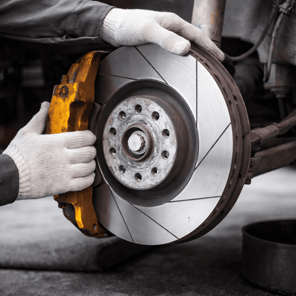 Meccanicien verifiant un disque de frein et un etrier sur une voiture