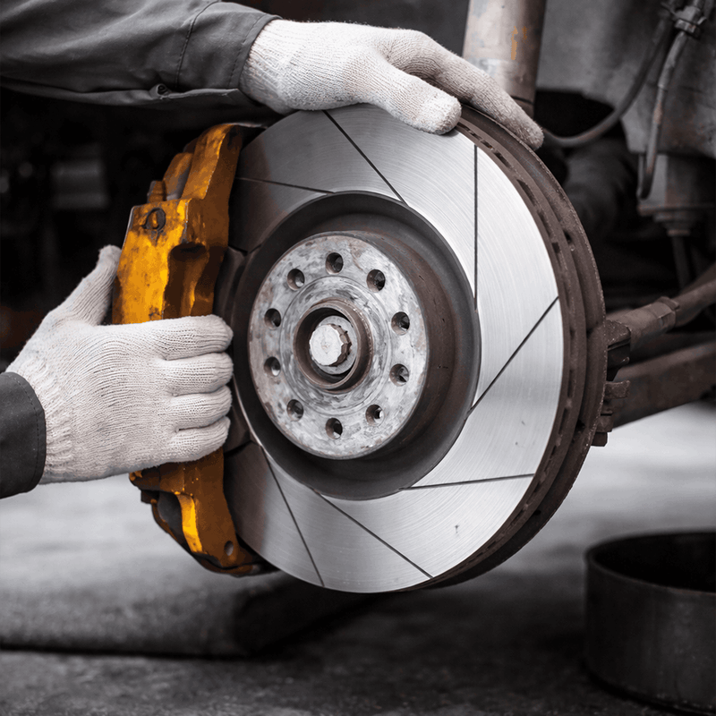 Meccanicien verifiant un disque de frein et un etrier sur une voiture