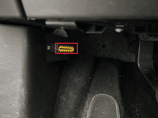 Port de diagnostic OBD2 jaune situé sous le tableau de bord côté conducteur