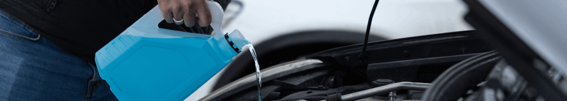 Ajout de liquide lave-glace bleu antigel dans le réservoir d'une voiture