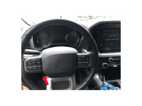 Gros plan sur le volant et le tableau de bord d'un pick-up Ford F150 avec une fleche rouge